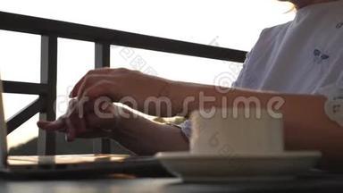 太阳下山时，一个女孩正在桌子旁用笔记本电脑和一杯咖啡工作